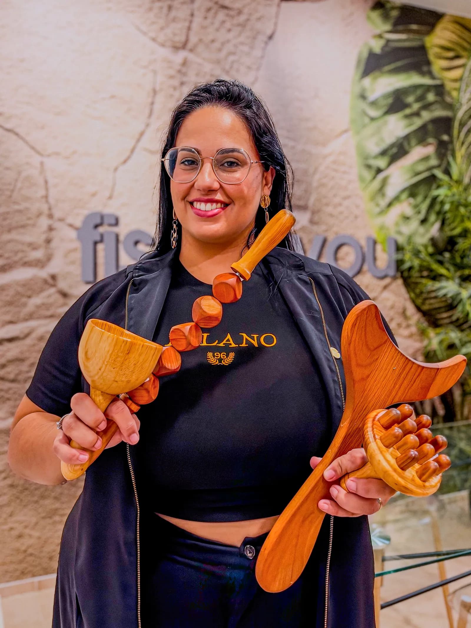 Angela Brazona, fisioterapeuta, com instrumentos de massagem em madeira